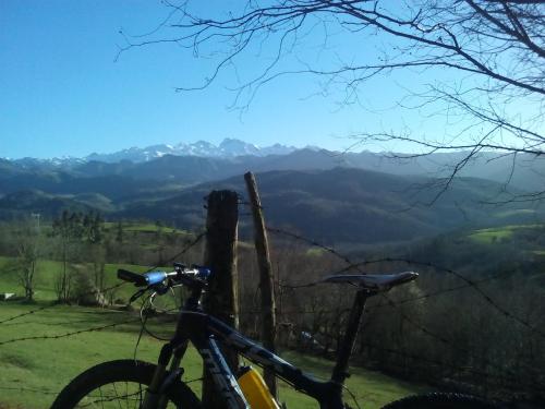 a bike parked next to a fence with mountains in the background at Pension Monteverde in Cangas de Onís