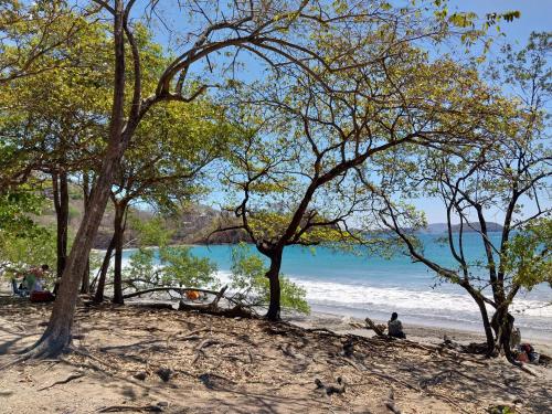 a group of people sitting on a beach near the water at Las Catalinas Loft - for up to 4 people just steps from the beach in Playa Danta