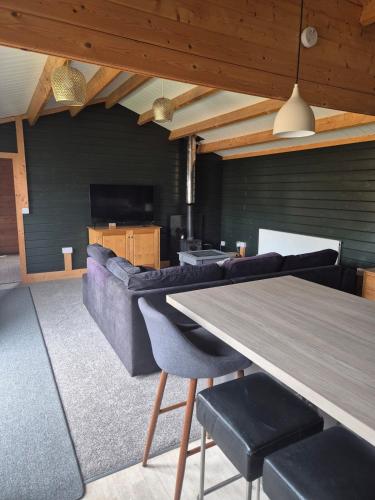 a living room with a table and a couch at Chalet close to Heathrow T5, Windsor Castle, Legoland, Thorpe Park, with off road parking, free Wifi, private garden, spacious & fully equipped, cozy wood burner & comfy sofa, ideal for exploring London with trains to Waterloo, a beautiful unique retreat in Colnbrook