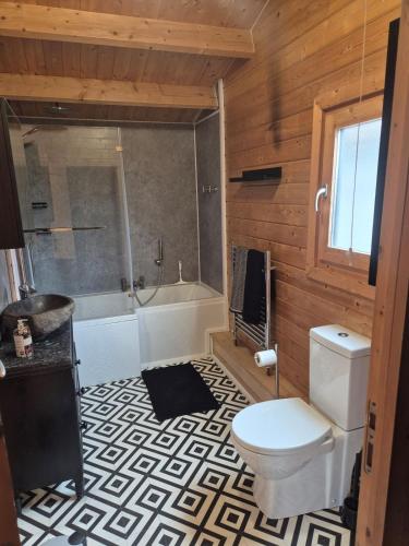 a bathroom with a toilet and a tub and a sink at Chalet close to Heathrow T5, Windsor Castle, Legoland, Thorpe Park, with off road parking, free Wifi, private garden, spacious & fully equipped, cozy wood burner & comfy sofa, ideal for exploring London with trains to Waterloo, a beautiful unique retreat in Colnbrook