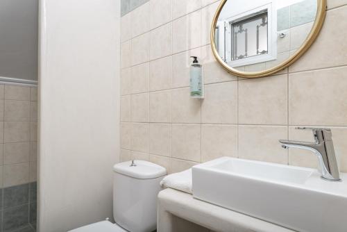 a bathroom with a toilet and a sink and a mirror at Naftilos Rosmarinus Apartments in Potokáki