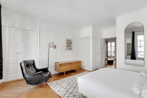 Cette chambre blanche comprend un lit, une chaise et un miroir. dans l'établissement Élégance & confort à deux pas de la Madeleine, à Paris