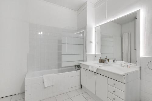 une salle de bain blanche avec un lavabo et un miroir dans l'établissement Élégance & confort à deux pas de la Madeleine, à Paris