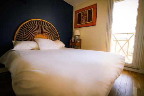 una camera da letto con un grande letto bianco con una grande finestra di La Maison Raspail - Calme Disney RER A a Neuilly-Plaisance