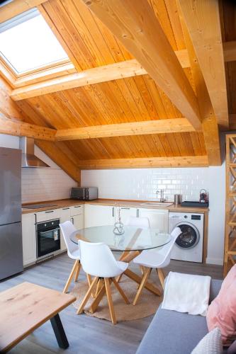 a kitchen with a dining table and white chairs at Via de la Plata Luxury Suites 2C in La Bañeza