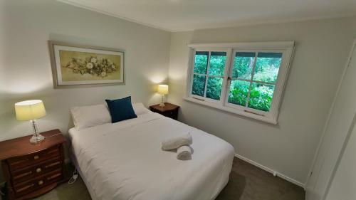 a bedroom with a white bed and two windows at Bellevue - Beautiful View in Mount Victoria