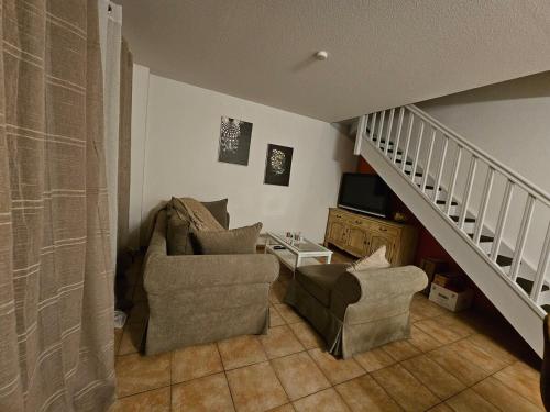 a living room with two chairs and a staircase at Logis de Gaia YourHostHelper in Homps