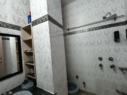 a bathroom with a shower and a sink and a mirror at SREA Homestead Dormitory in New Delhi