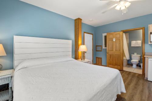 a bedroom with a large white bed and a bathroom at Courtyard Villas On Silver Lake in Ocracoke