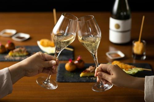 two people holding glasses of white wine on a table at Courtyard by Marriott Shin-Osaka Station in Osaka