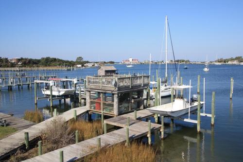 a dock with boats docked on the water with a house at Courtyard Villas On Silver Lake in Ocracoke