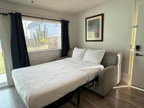 a bed with a chair in a room with a window at Unit 109 -1br Apt Oceanfront Complex With Pool in Cocoa Beach