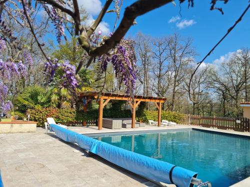 - une piscine avec un kiosque et des fleurs violettes dans l'établissement Appartement Type F4, à Maurens