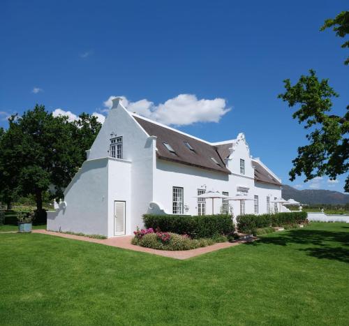 a large white house with a green lawn at Adara Palmiet Valley Luxurious Boutique Farm Hotel in Paarl