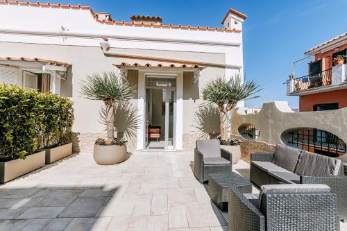 a patio with chairs and trees in front of a building at Villa Amato Rooms & Apartment in Ischia