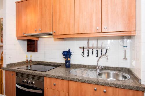 Una cocina con gabinetes de madera y un fregadero. en Apartamento céntrico Belquimar a pocos pasos de la playa, en Carboneras