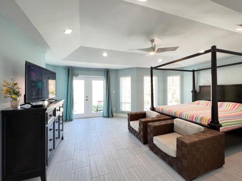 a bedroom with a bed and a tv and a couch at Fam Reunion, Beachview, EV charger Heated Pool, Jacuzzi, Billiard in South Padre Island