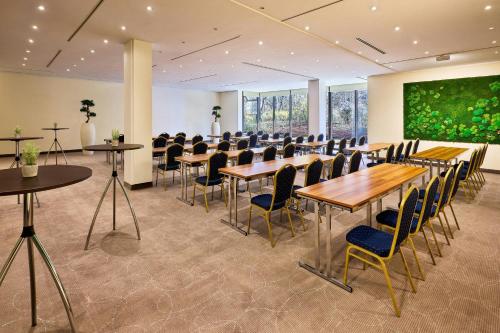 a conference room with tables and chairs and a large screen at The Westin Leipzig in Leipzig