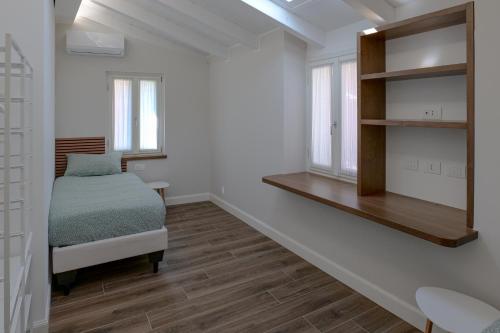 a white room with a bed and a shelf at Super Attico in Verbania