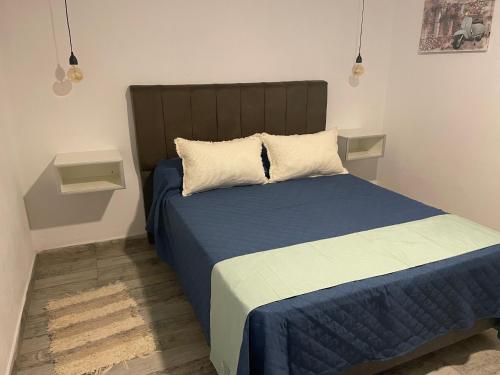 Un dormitorio con una cama con una manta azul y almohadas. en Vallenegro departamentos, en Malargüe