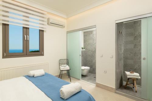 sypialnia z niebieskim łóżkiem i łazienką w obiekcie Minimalist Mediterranean Blue key Villa with Sea View & Infinity Heated Pool w mieście Agia Pelagia