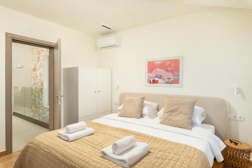 a bedroom with a large bed with towels on it at Minimalist Mediterranean Blue key Villa with Sea View & Infinity Heated Pool in Agia Pelagia