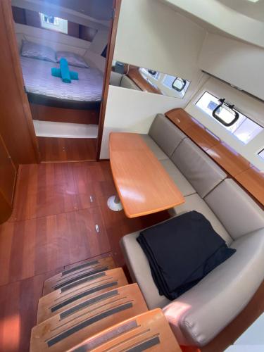 Cette petite chambre comprend un canapé, un lit et une table. dans l'établissement Une nuit inoubliable sur un bateau Linge et ménage inclus, à La Rochelle