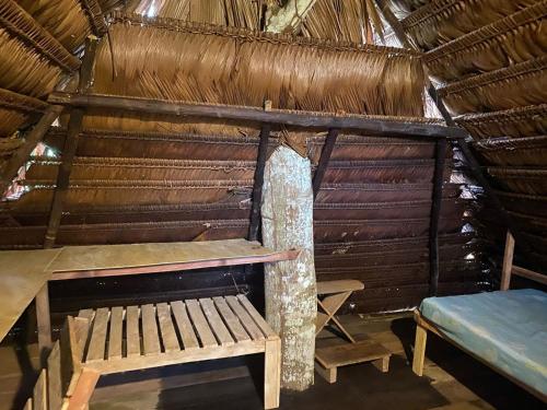 a man standing in a hut with a table and bench at Casa do Xingú in Leticia