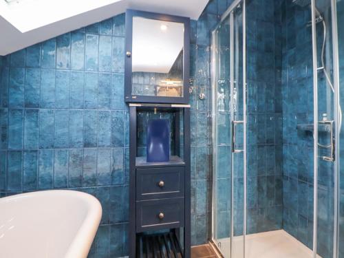 baño con paredes de azulejos azules y ducha. en The Alhambra, en Southport