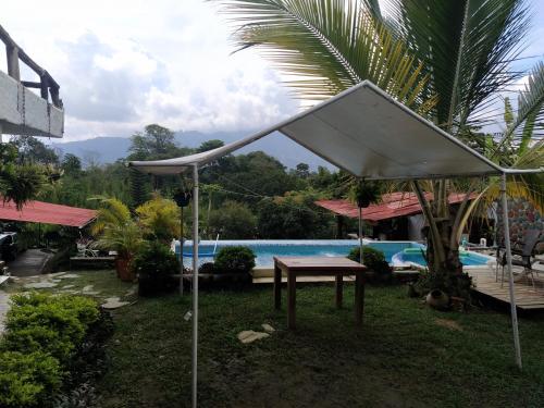 un tavolo con ombrellone di fronte alla piscina di Casa Campestre la casona de la loma a Ibagué