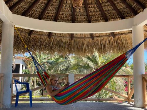 a woman laying in a hammock under a straw umbrella at Beachfront Paradise Boutique Hotel - Breeze Room ll in Playa Agua Blanca