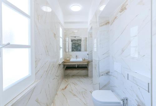 a white bathroom with a toilet and a sink at Villa Amato Rooms & Apartment in Ischia