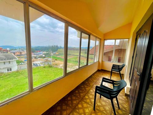 an empty room with two chairs and large windows at Teyt Castle Ooty in Ooty
