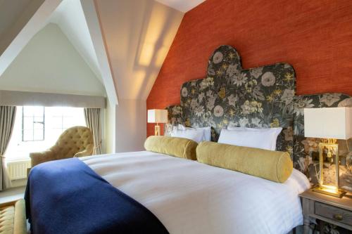 a bedroom with a large bed with a red wall at Billesley Manor Hotel & Spa, a Tribute Portfolio Hotel in Stratford-upon-Avon