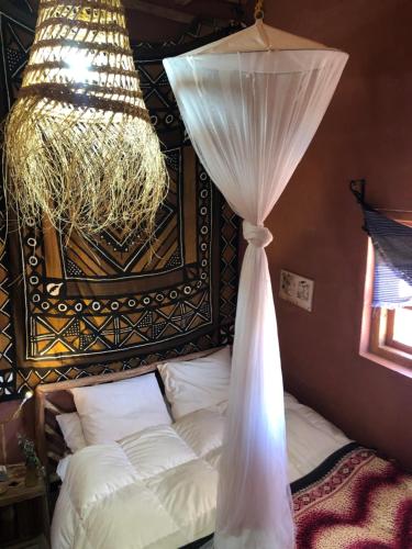 a bedroom with a bed with a curtain and a chandelier at Chill and welcoming flat in Tagounite in Tagounite