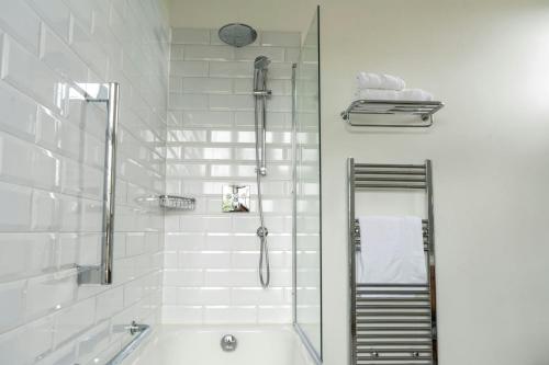 a white bathroom with a tub and a shower at Billesley Manor Hotel & Spa, a Tribute Portfolio Hotel in Stratford-upon-Avon
