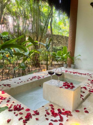 two glasses of wine sitting on a table with roses pedals at Piedra de Agua Palenque in Palenque