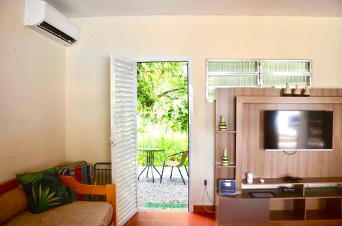 a living room with a television and a sliding glass door at Casa com piscina 500m da praia condomínio Morada da Praia in Bertioga