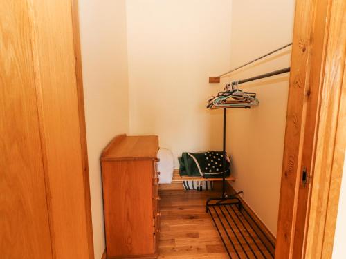 a hallway with a wooden cabinet and a chair in a room at Cúnna Bán in Derreen
