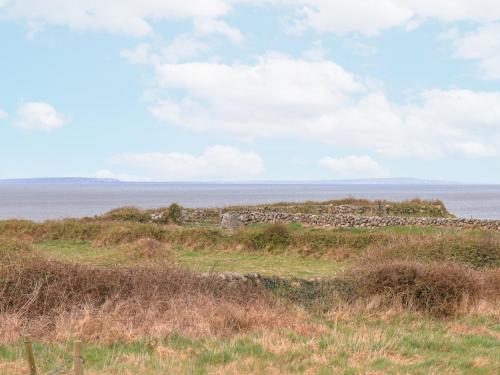a stone wall on a hill next to the ocean at Cúnna Bán in Derreen