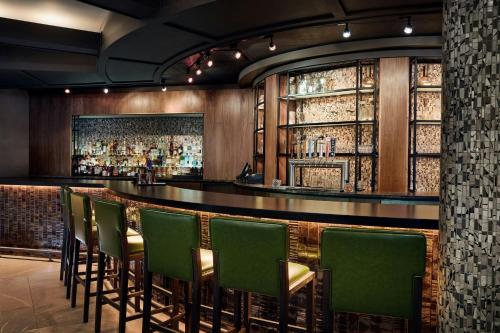 a bar with green chairs in a room with windows at Fort Collins Marriott in Fort Collins