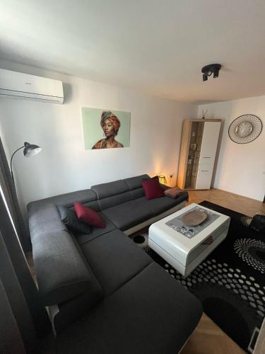 a living room with a black couch and a table at VITRUVIAN Apartament 13 - Self check in 24h in Reşiţa
