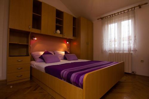 a bedroom with a bed with purple sheets and a window at Apartments Dario in Krk