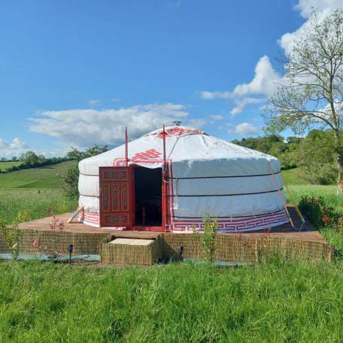une grande tente en forme de dôme installée dans un champ dans l'établissement Yourte calvados, à Les Moutiers-en-Auge