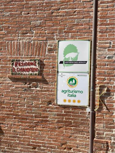 two signs on the side of a brick wall at Il Ghiandolino in Imola