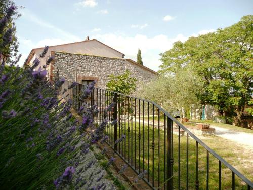 a fence in front of a stone building with purple flowers at Marco & Andrea Agriturismo Collepina in Amelia