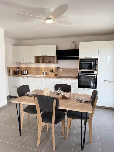 Il comprend une cuisine avec une table en bois, des chaises et un ventilateur de plafond. dans l'établissement Le Doublaix - Superbe T3 neuf - Parking privé -, à Aix-les-Bains