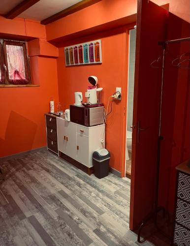 une chambre orange avec une cuisine équipée d'un four micro-ondes dans l'établissement Chambre indépendante, à Saint-Chély-dʼApcher