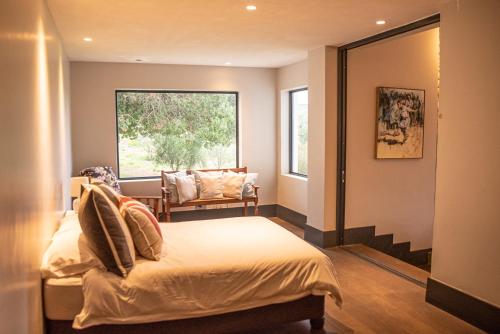 a bedroom with a bed and a window and a chair at Oudewerfskloof Olive Farm in Stilbaai