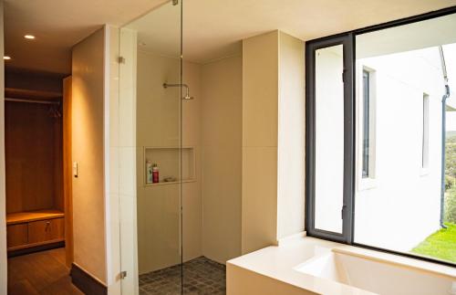 a bathroom with a shower and a sink and a window at Oudewerfskloof Olive Farm in Stilbaai